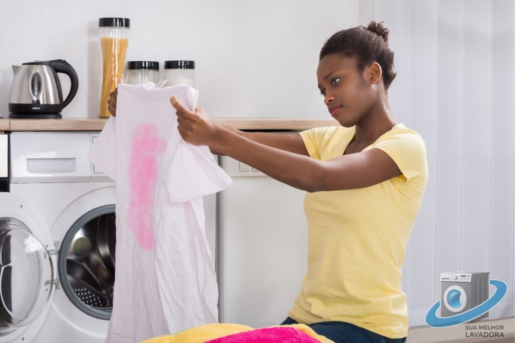 A imagem ilustra uma mulher com uma expressão de surpresa ao descobrir uma mancha na roupa, causada por depósitos de sujeira que se soltaram da máquina durante a lavagem
